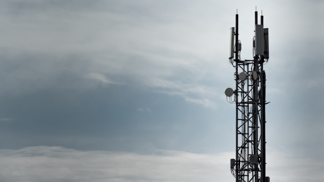 Mobilo sakaru tornis uz mākoņainas debess fona